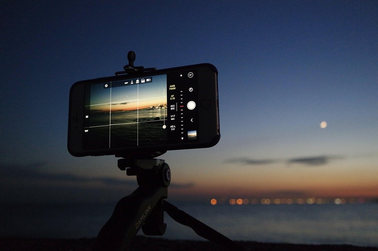 Smartphone fixé sur un trépied photographiant un coucher de soleil en bord de mer