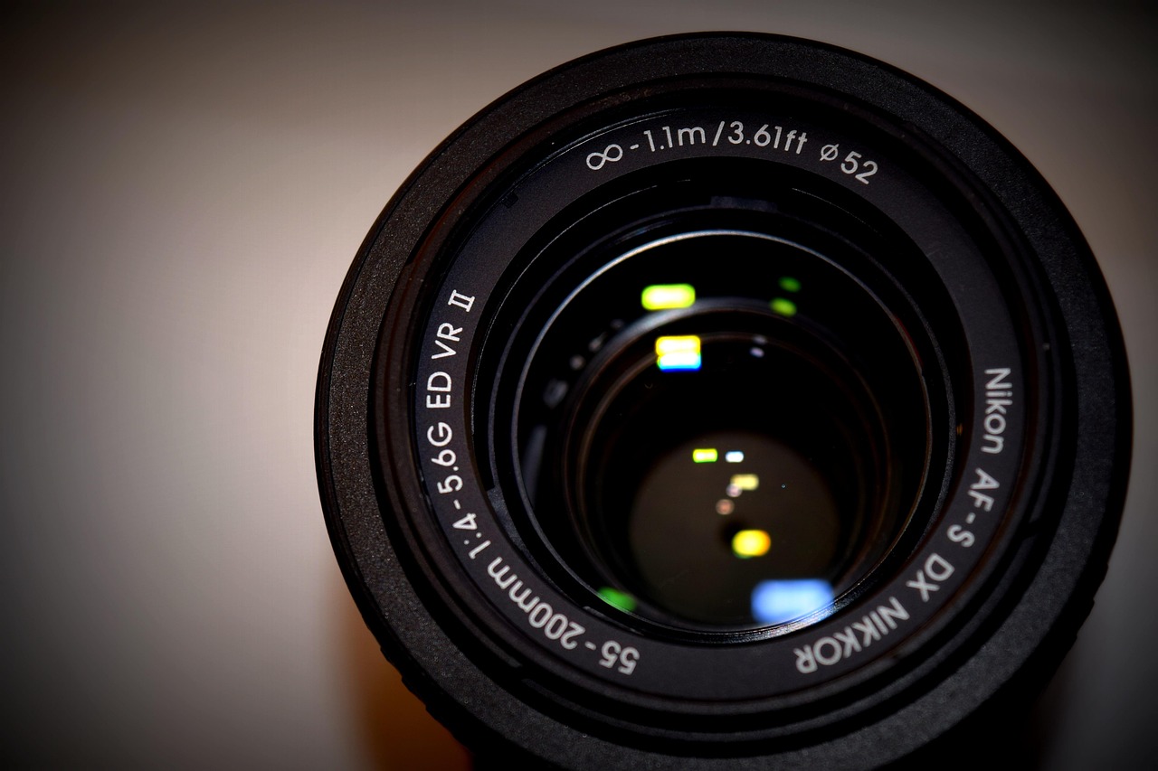 Gros plan sur un objectif photo Nikon avec reflets lumineux sur la lentille.